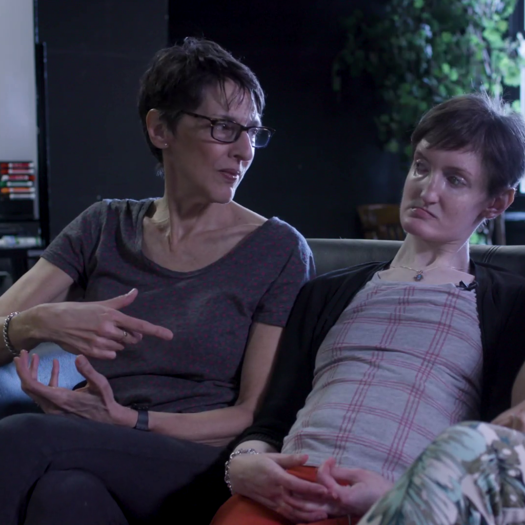 Faye, Sam's mom, and Sam, sit on the couch.